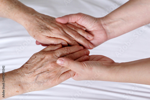 Wrinkled hands of senior woman in the palms of a young woman. Concept of care and support, elderly mother and daughter