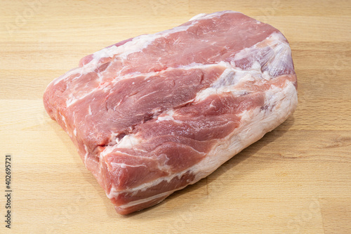 A big piece of raw red pork meat on wooden cutting board, preparing for make a steak. Food close-up photo. 