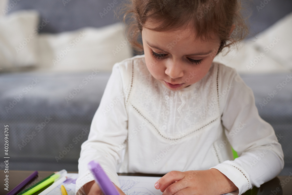 Closeup of a cute little girl in white shirt drawing with color pencils at home Closeup of a cute little girl in white shirt drawing with color pencils at home