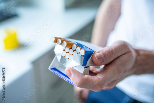 Giving someone a cigarette. Pack of cigarettes in a male hand. Smoking habit.