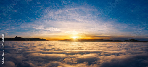 Sunset sky in the mountains above thick fog over the clouds.