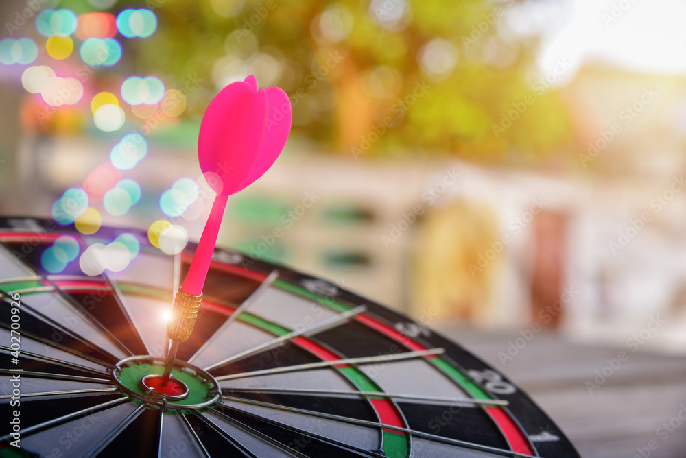 Fototapeta premium Red Darts arrow hitting on center of Dartboard with bokeh to target success in business the game focuses on success, planning to be smart concept..