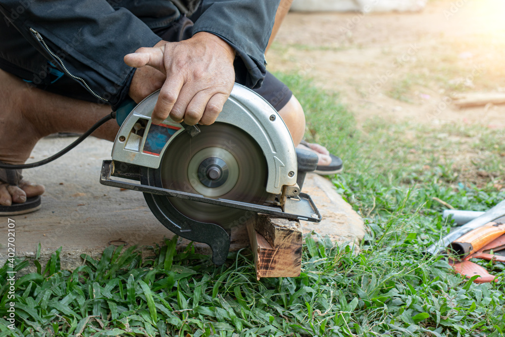 A carpenter is using a circular saw to cut the log. A carpenter is using a circular saw to cut the log.