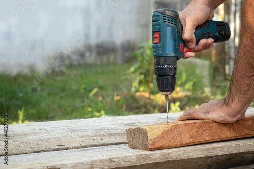 The carpenter was using an electric drill to drill into the wood.