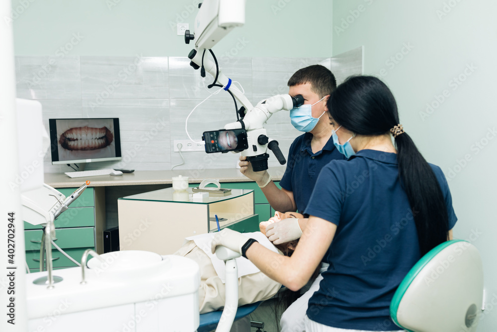 Medical Stomatology Concept. Doctor making teeth examination research survey using microscope in dentistry. Dentist is treating patient in modern dental office Medical Stomatology Concept. Doctor making teeth examination research survey using microscope in dentistry. Dentist is treating patient in modern dental office