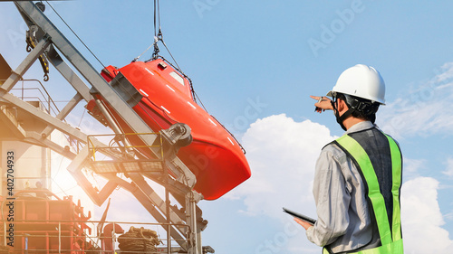 Photography Lifeboat maintenance at stern ship, Under the Rescue boat or lifeboat Under Repairing on lifting control by surveyor at dry dock in shipyard Thailand