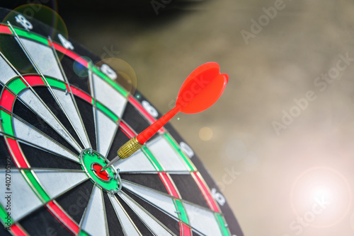 Success hitting target aim goal achievement concept background – three dart in bull’s eye close up, on dark tone background.