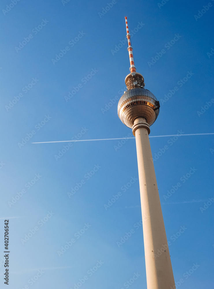 Fototapeta premium Berlin TV tower against a blue sky with a trail from the plane.