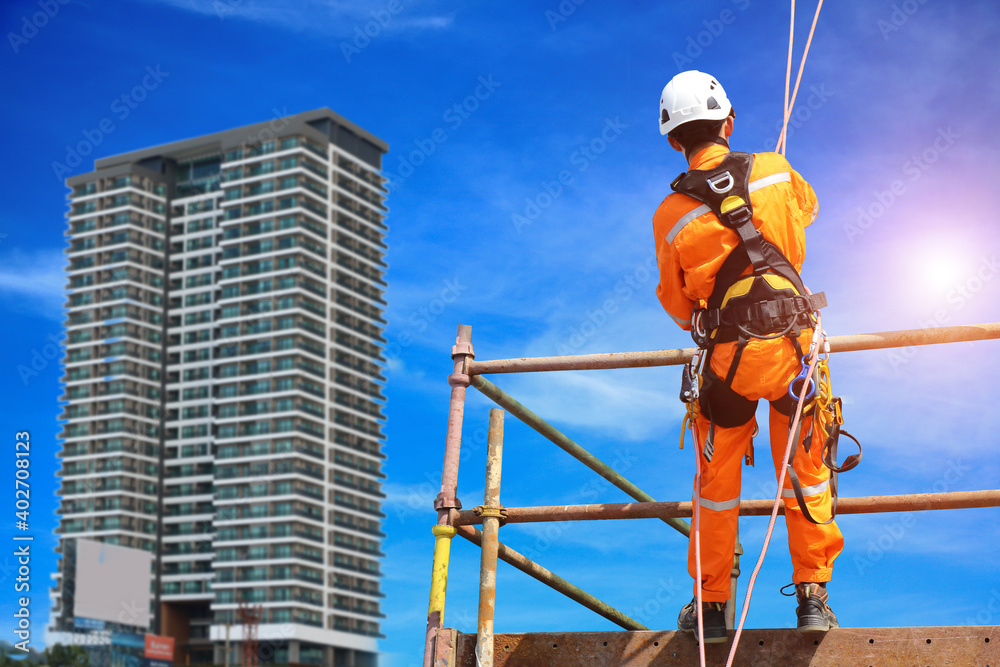Safety man worker sprinkle on scaffolding from tower climber on building with blue sky background.