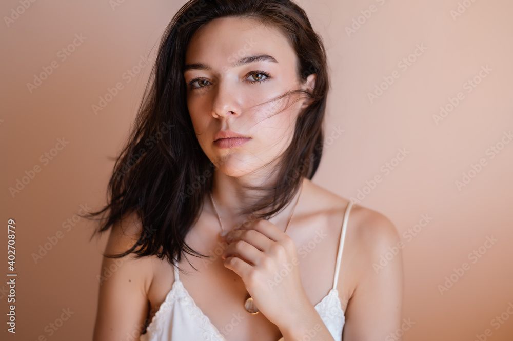 Beautiful young woman posing on beige wall background. Beautiful young woman posing on beige wall background.