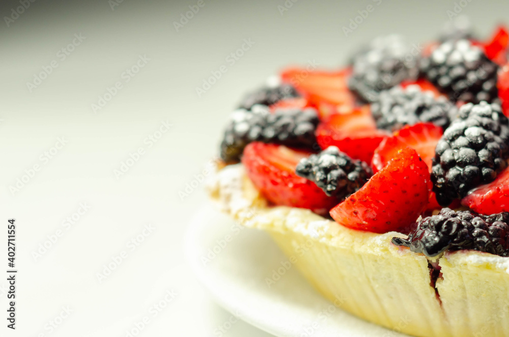 Butter enriched shortcrust pastry topped strawberries and blackberries, seasonal cake with colorful decoration Butter enriched shortcrust pastry topped strawberries and blackberries, seasonal cake with colorful decoration