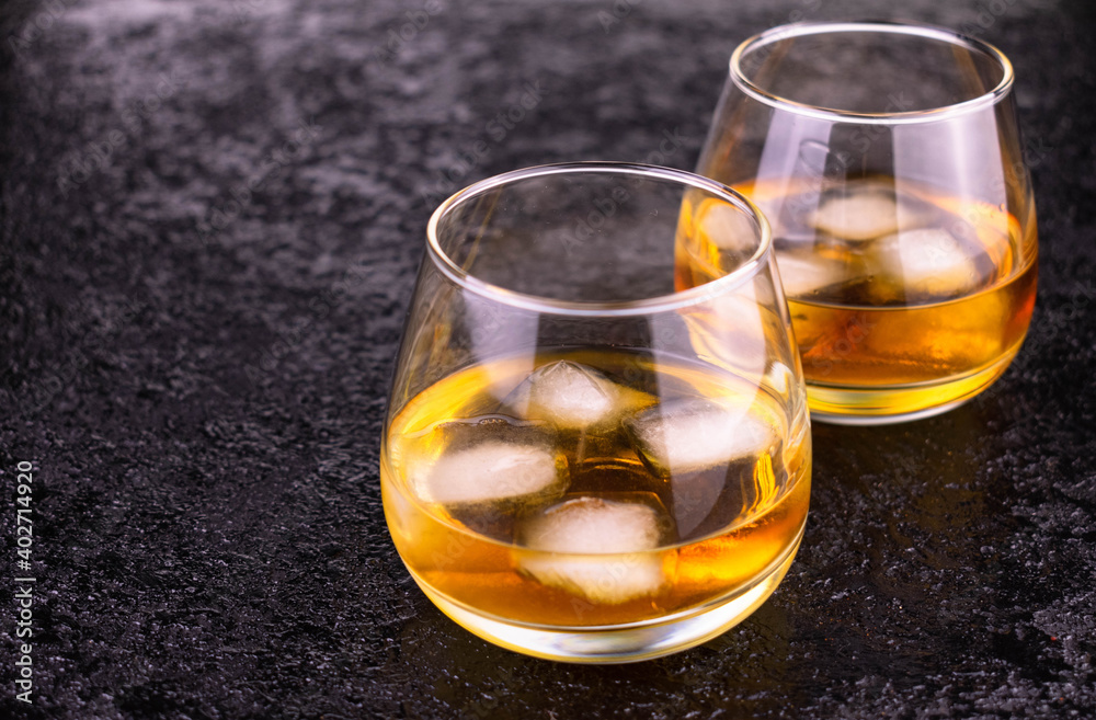 Two glasses of cognac with ice on a black background.
Copy space. Two glasses of cognac with ice on a black background.
Copy space.