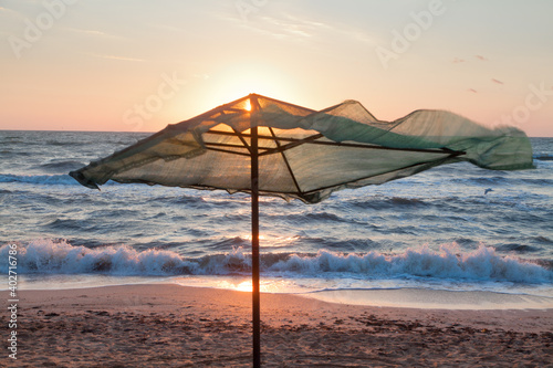 Sunrise over the sea beach  beach umbrella in the foreground.