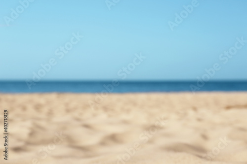 Blurred view of beautiful sandy beach and sea on sunny day. Summer vacation