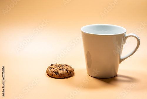 Close up white mug of milk and dark chocolate chip cookie