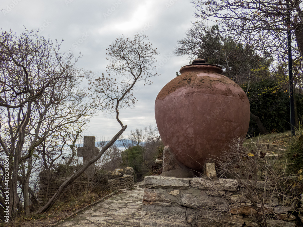 Obraz premium Big ceramic pot in the autumn botanical garden. Plants with autumn leaves around.