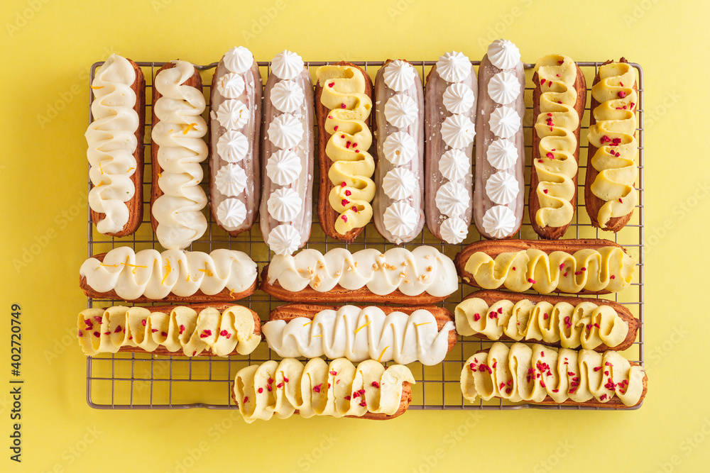 Set of fresh eclairs with original butter cream and meringue cookies decoration. French pastry on the yellow background. Flat lay Set of fresh eclairs with original butter cream and meringue cookies decoration. French pastry on the yellow background. Flat lay