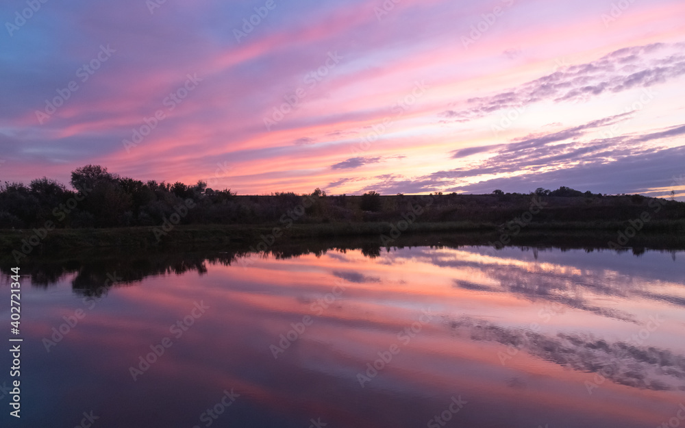sunset over the river, the sky is reflected in the water, there is a small bridge on the river bank sunset over the river, the sky is reflected in the water, there is a small bridge on the river bank