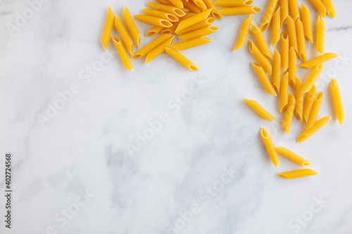 penne pasta spilling out onto a marble conutertop from a blue box