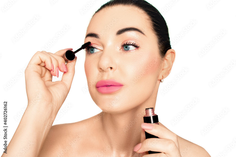 Portrait of a girl on a white background. She applies mascara to her lashes.. Portrait of a girl on a white background. She applies mascara to her lashes..