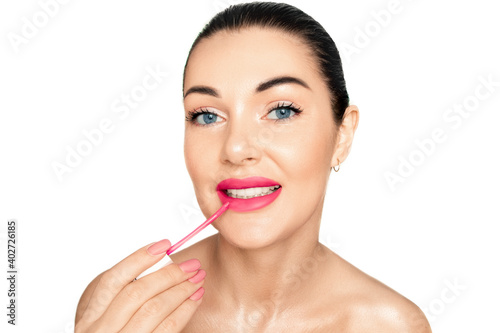 Portrait of a girl on a white background. Applies pink lipstick to lips..