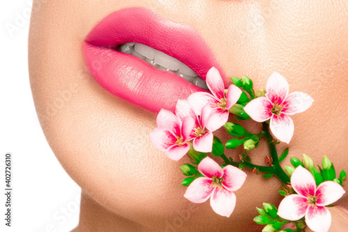 Girl lips with pink lipstick. There are pink flowers around the lips..