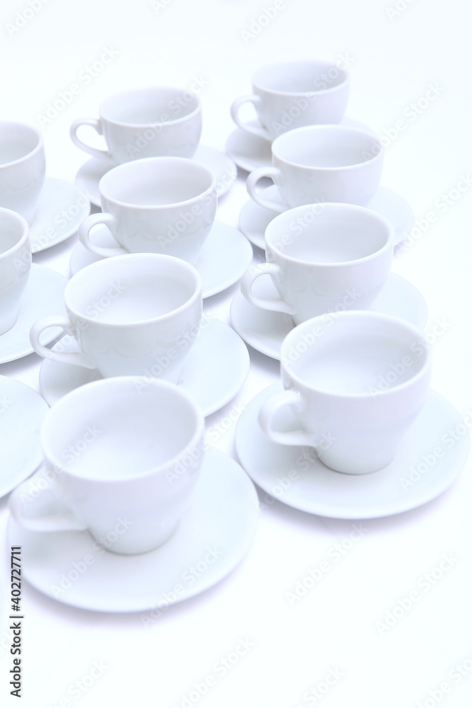 Tea pairs of white porcelain or ceramics on the table. Dishes for serving a large number of people at a holiday or event. View from above. Vertical photo. Tea pairs of white porcelain or ceramics on the table. Dishes for serving a large number of people at a holiday or event. View from above. Vertical photo.