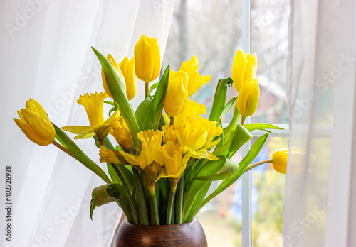 Bouquet of yellow tulips and daffodils  in a vase. Easter and spring greeting card. Women's day, March 8.