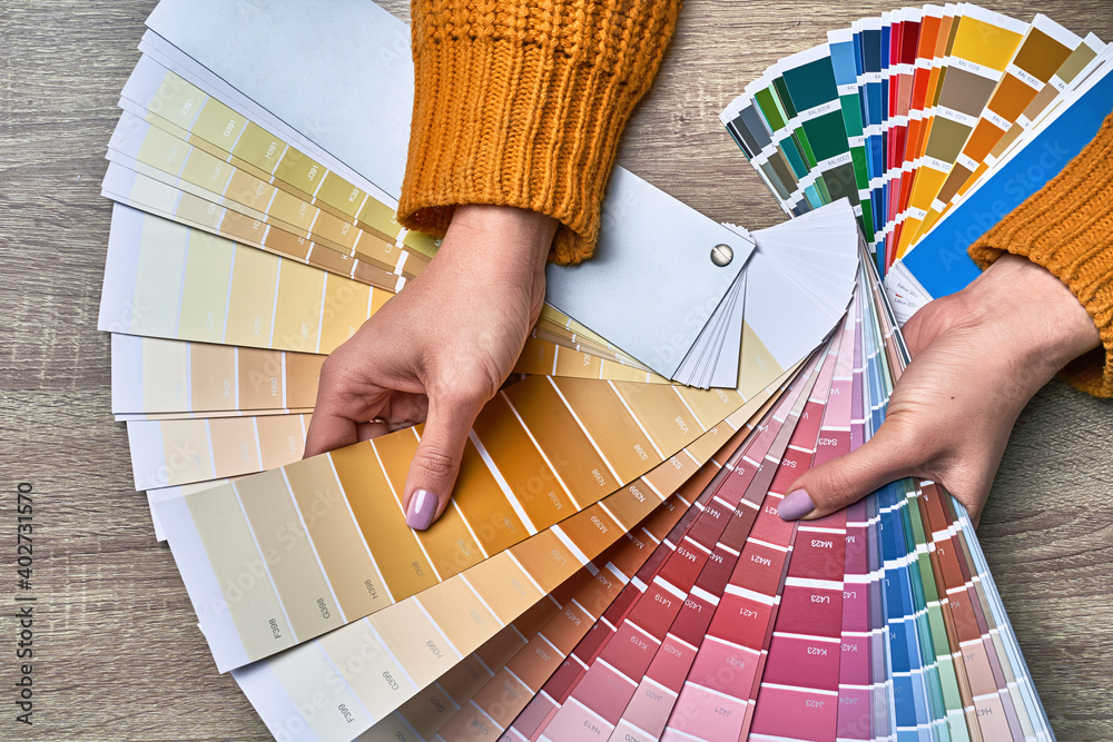 Color wheel for choosing paint tone. Hands of female interior designer working with palette for choosing colors. Creative process concept. Comparing options with matching hues.