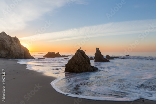 white foamy waves on rocky Malibu Beach in California at sunrise