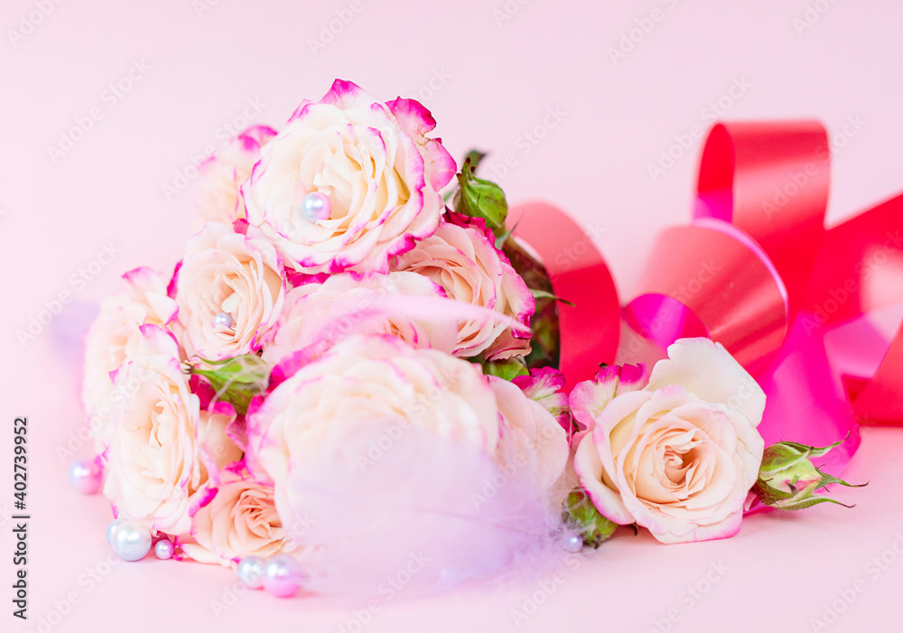 Fototapeta premium delicate bouquet of bushy peony roses with bright ribbons, pearls, feathers and hearts on a pink background, the concept of congratulations on Valentine's day