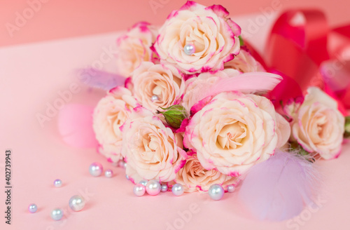 delicate bouquet of bushy peony roses with bright ribbons, pearls, feathers and hearts  on a pink background, the concept of congratulations on Valentine's day © klavdiyav
