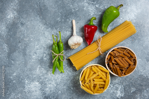 Photos Raw spaghetti with vegetables on a wooden board
