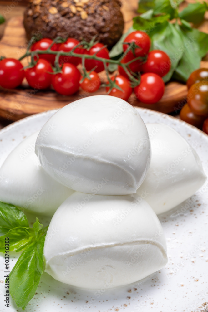 Cheese collection, white balls of soft Italian cheese mozzarella, served with red cherry tomatoes, fresh basil leaves Cheese collection, white balls of soft Italian cheese mozzarella, served with red cherry tomatoes, fresh basil leaves
