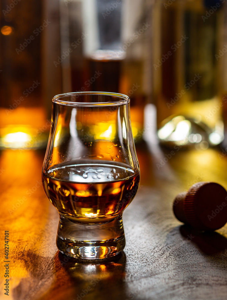 Dram of single malt scotch whisky and bottles on background Dram of single malt scotch whisky and bottles on background