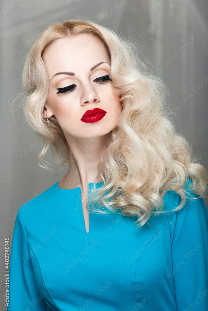 Beautiful young blonde woman with curly hair and makeup, in blue dress. Beautiful young blonde woman with curly hair and makeup, in blue dress.