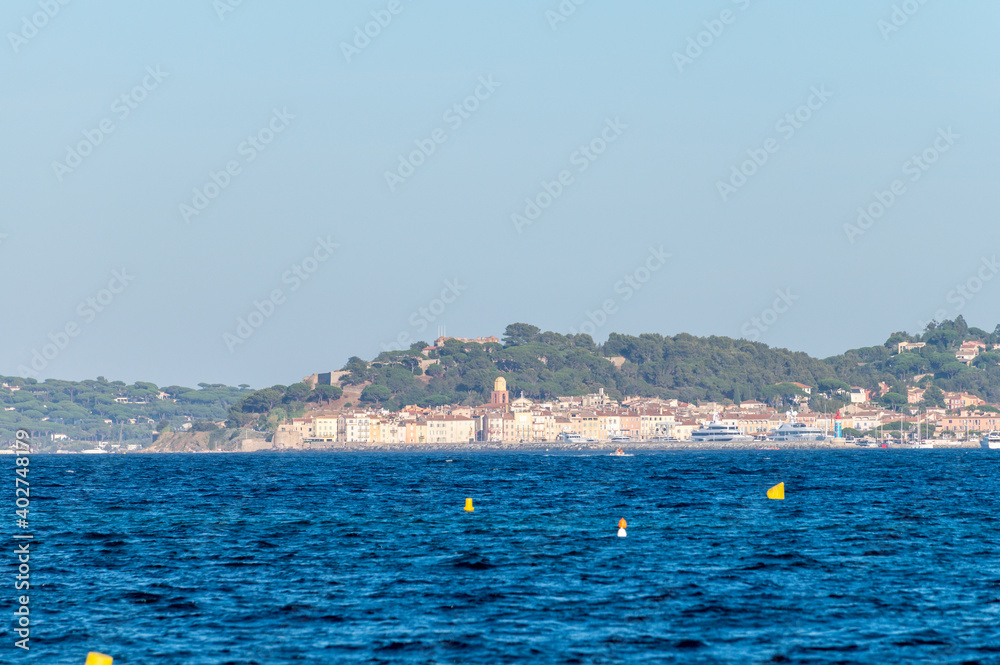 Blue water of Gulf of Saint-Tropez with outlines of Saint-Tropez town on background, French Riviera, France