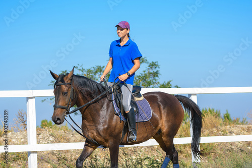 Pretty girl in casual clothes rides a horse