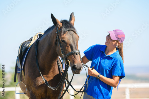 Happy beautiful girl looking at a horse on a warm summer day © madhourse