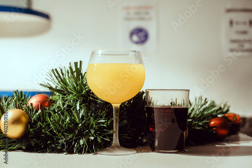 Dos vasos de bebida alcohólica en la barra de un bar junto a decoraciones de Navidad como un espumillón y bolas doradas photo