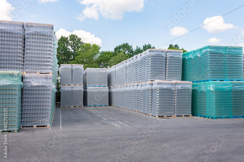 The open air storage and carriage of the finished product at industrial facility. A glass clear bottles for alcoholic or soft drinks beverages and canning jars stacked on pallets for forklift.