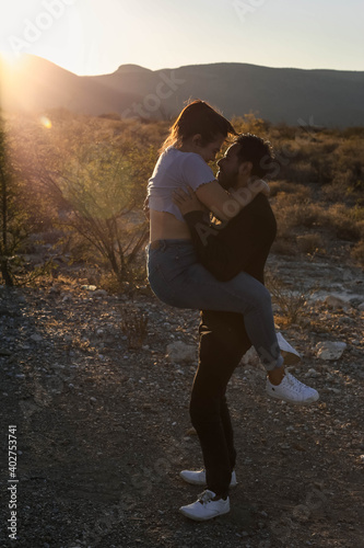 Couple kissing on the mountains with beautiful sunset in background
