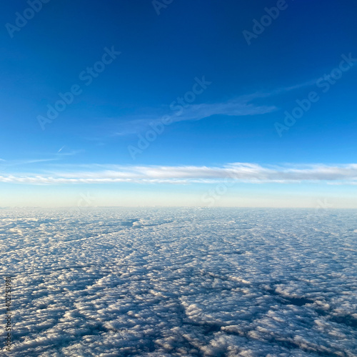 Fototapeta Naklejka Na Ścianę i Meble -  An aerial view from an airplane window of clouds with blue skies.