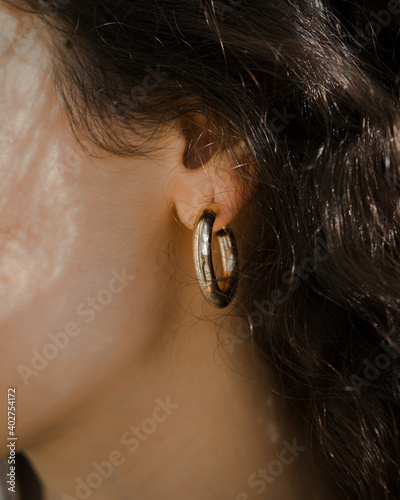 Side view of a woman's face wearing a gold hoop earing.