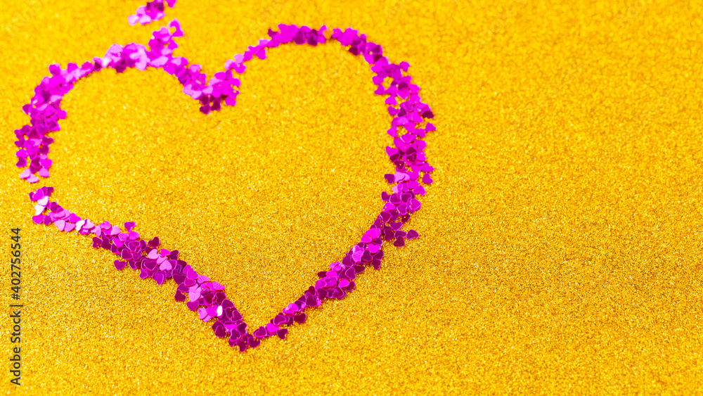 Heart shape made of multicolored glitter. Confetti in the shape of a heart over golden glitter background. Valentine's Day concept. Copy space. Top view Heart shape made of multicolored glitter. Confetti in the shape of a heart over golden glitter background. Valentine's Day concept. Copy space. Top view