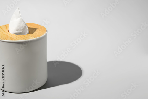 Holder with paper tissues on light grey background, closeup. Space for text