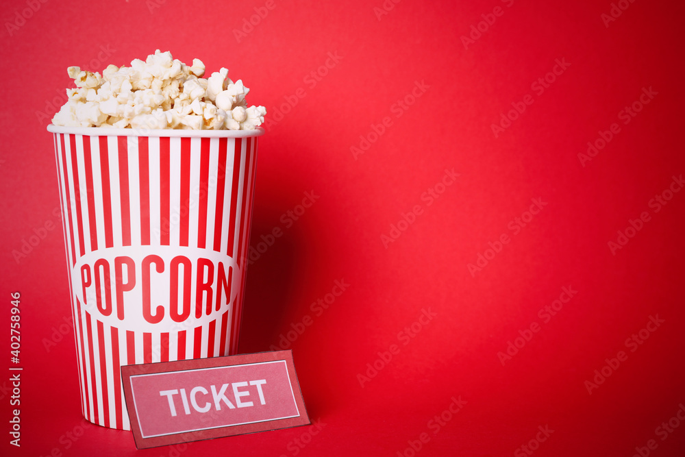Delicious popcorn and ticket on red background. Space for text
