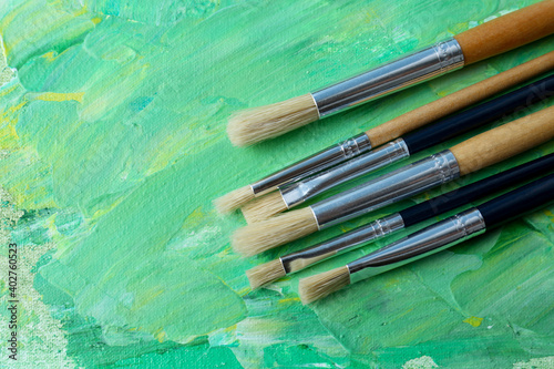 Set of different brushes on abstract colorful paint, flat lay