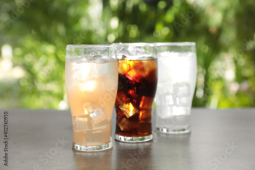 Delicious refreshing drinks in glasses on grey table outdoors