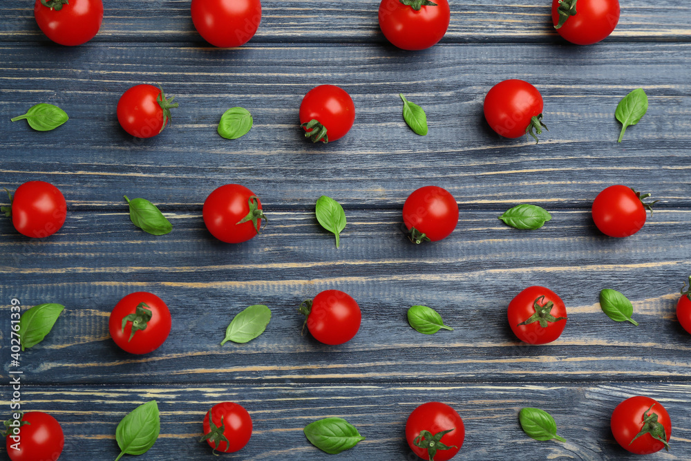 Flat lay composition with fresh cherry tomatoes and basil leaves on blue wooden table